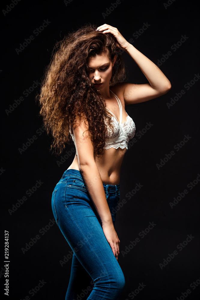 portrait of beautiful woman in white bra and jeans posing isolated on black portrait of beautiful woman in white bra and jeans posing isolated on black