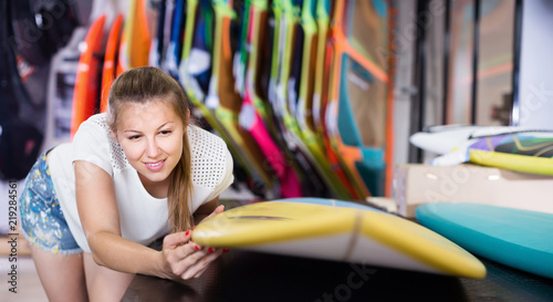Portrait of positive female who is choosing surfboard