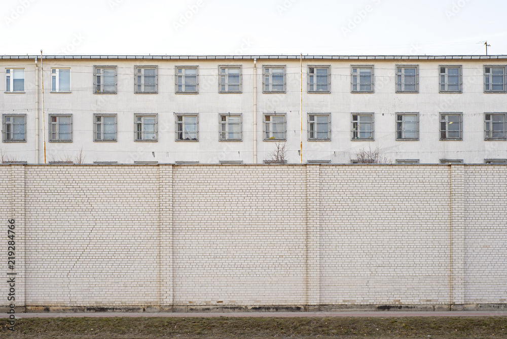 Abandoned building surrounded by big white brick wall. Industrial background.
