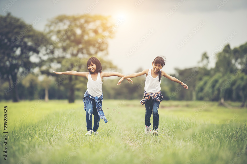 Two little cute girls are running on green grass. Best friends. Two little cute girls are running on green grass. Best friends.