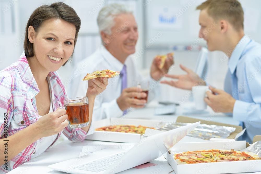 Portrait of businesspeople eating pizza in office