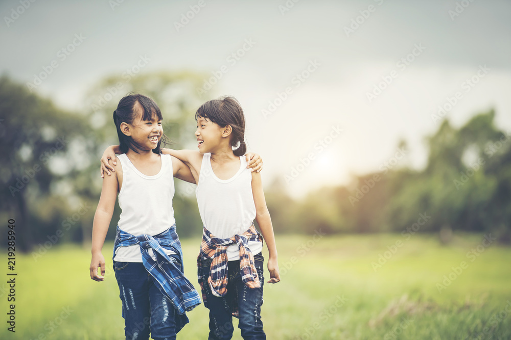 Two little girls hand holding together having fun in the park Two little girls hand holding together having fun in the park