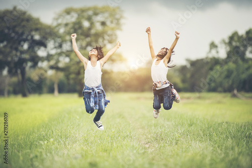 Two little girls happy jump in the nature park