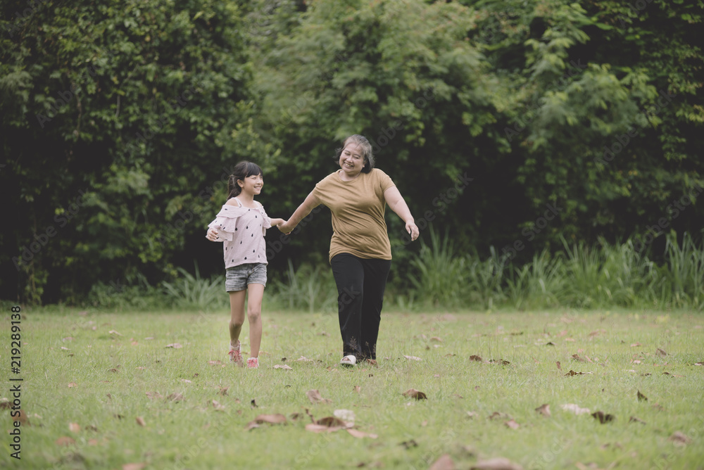 Obraz premium Grandmother and granddaughter enjoyed in the garden; a little girl kissing on the her grandmother's face.