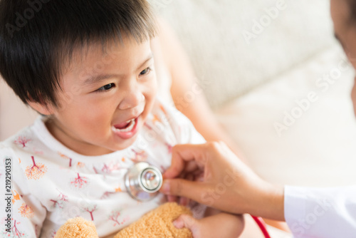 Doctor examining a little girl by using stethoscope. Medicine and health care concept.