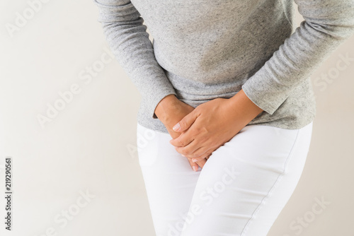 Young woman having painful stomachache with hands holding pressing her crotch lower abdomen. Medical or gynecological problems, healthcare concept