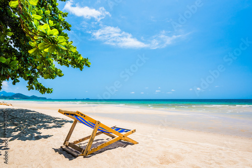 Tropical tree and beach chair at white sand beach and blue sea © songdech17