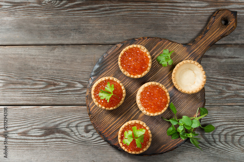 Red caviar in tartlets on a wooden table