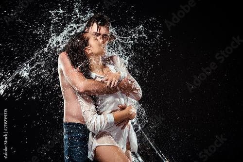 portrait of seductive couple with water splash isolated on black