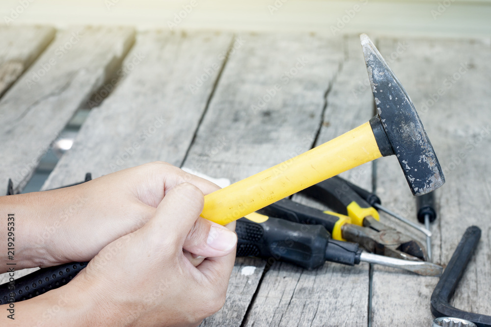 Hold a hammer with two hands and a Screwdriver,wrench on a wooden table.