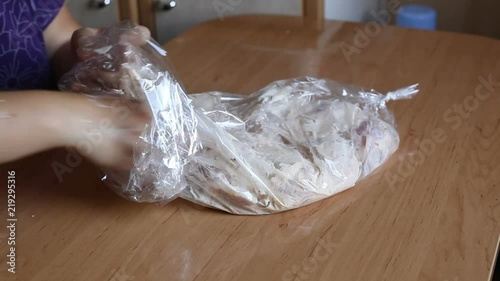 the cook puts pieces of chicken in a plastic sleeve. Video close-up, high quality