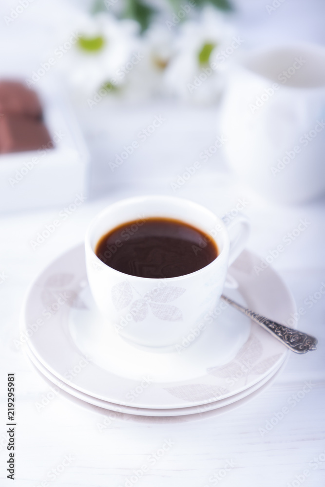 Porcelain cup of black coffee and chrysanthemums flowers on a white background Porcelain cup of black coffee and chrysanthemums flowers on a white background