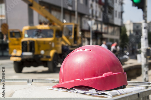 The helmet on the construction plans and buildings in the background