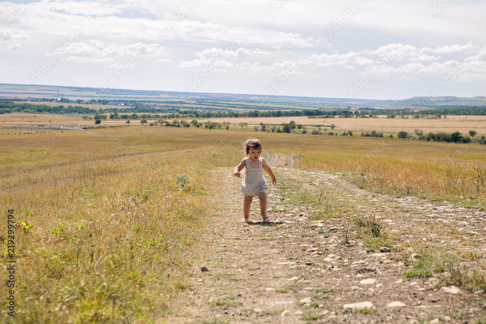 baby boy running across the field at sunset in summer baby boy running across the field at sunset in summer