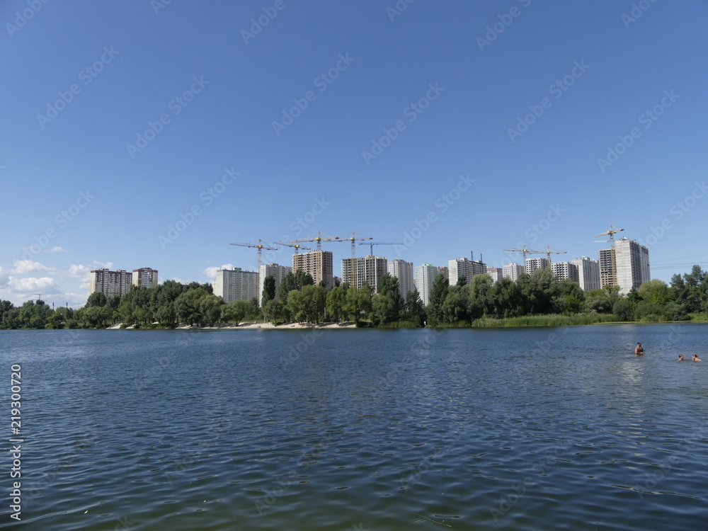 A lake against the background of houses under construction. Skys