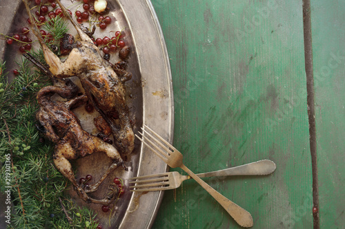 Cooking fried woodcock or snipe in hot butter with red currant. Outdoors. photo