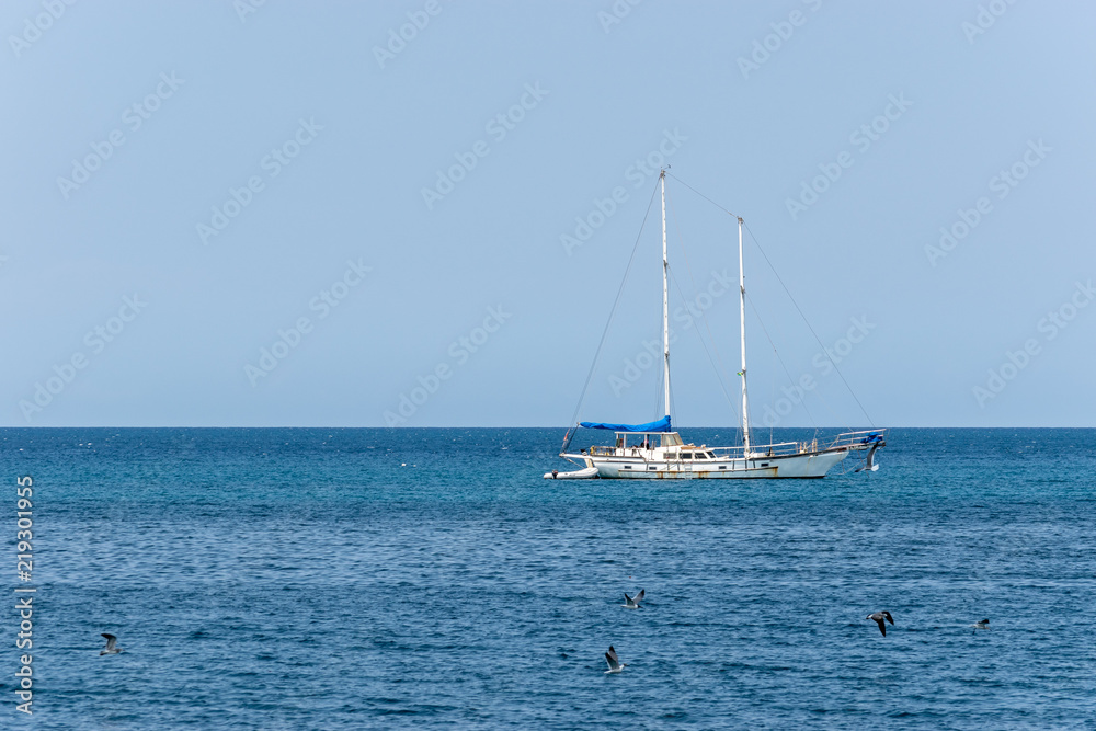Old white yacht sailing the calm ocean on sunny day in the Caribbean