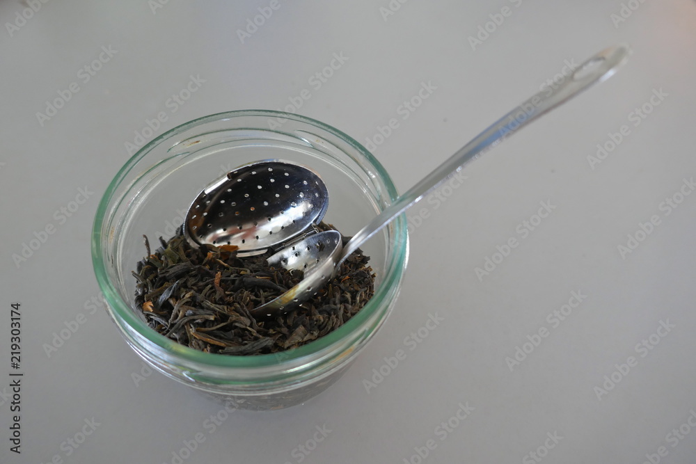 Trockener grüner Tee mit einem silbernen Löffel mit Teefilter in einem Aufbewahrungsglas
Trockener grüner Tee mit einem silbernen Löffel mit Teefilter in einem Aufbewahrungsglas
