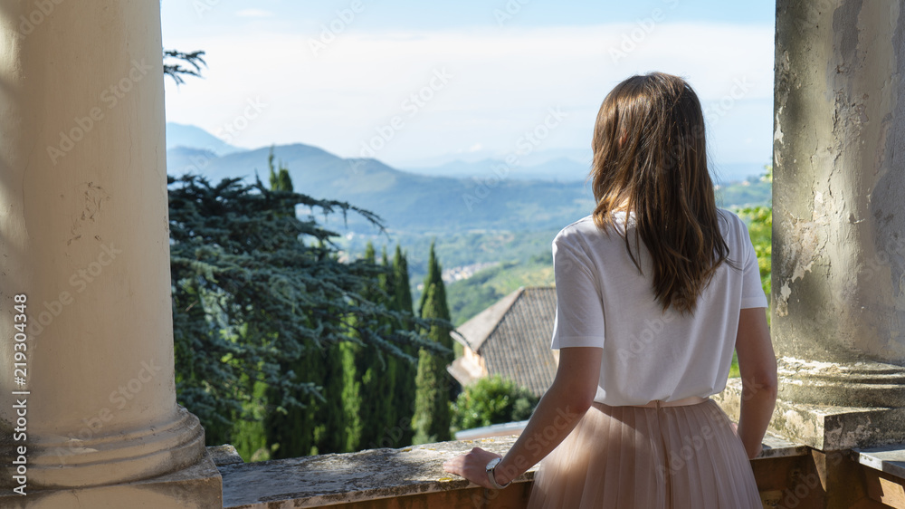 Girl looks from a balcony in an old villa
