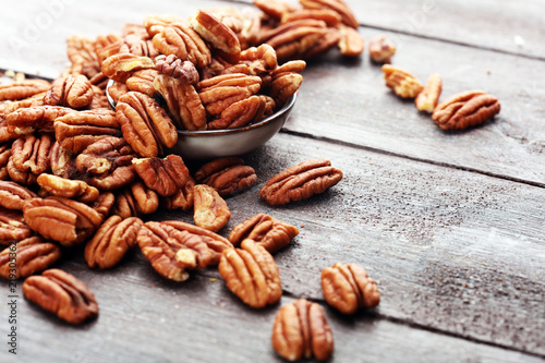 Pecan nuts on a rustic wooden table and pecan nuts in bowl