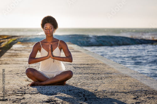 Mysterious Young African American Woman Meditating by the Sea 