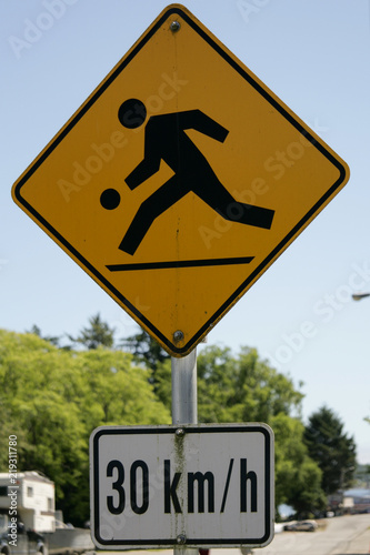 Funny yellow street sign showing children playing at 30 kmph photo