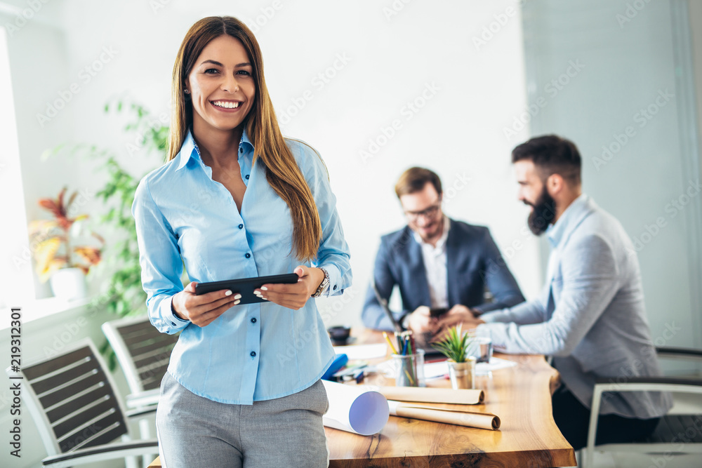 Fototapeta premium Portrait of young businesswoman using digital tablet while colleague in background