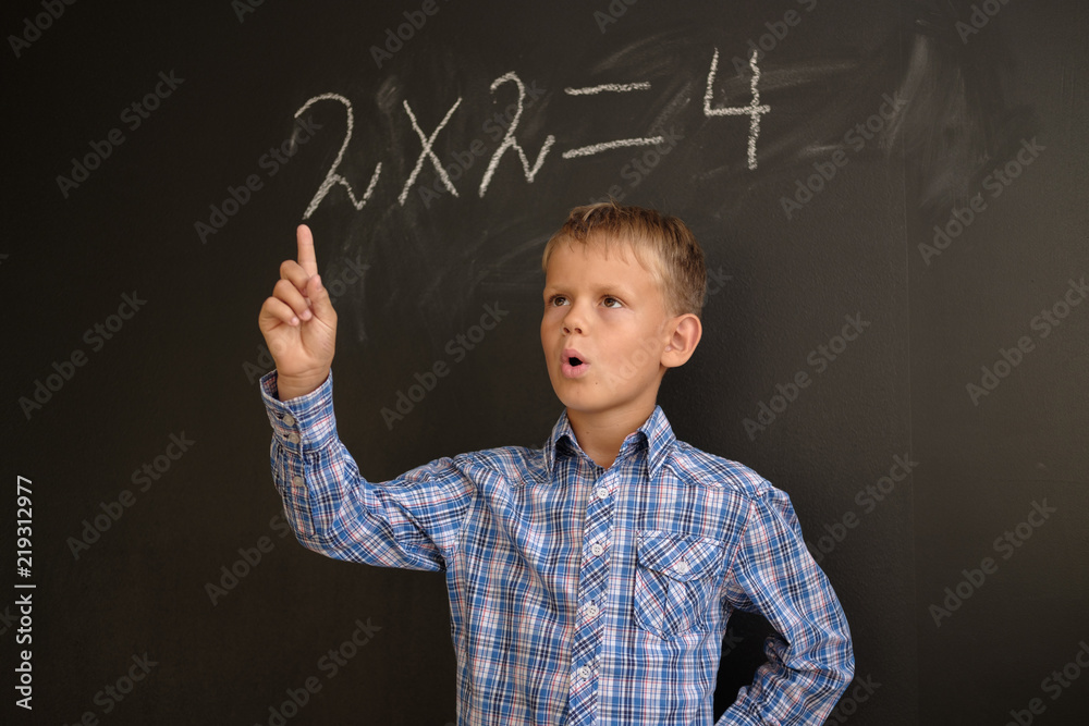 European boy thinking about solving a mathematical problem, standing at the blackboard European boy thinking about solving a mathematical problem, standing at the blackboard