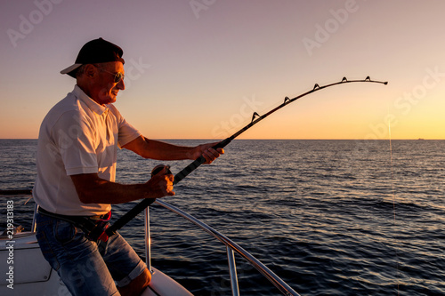 angler fishing on the sea from the boat at sunset