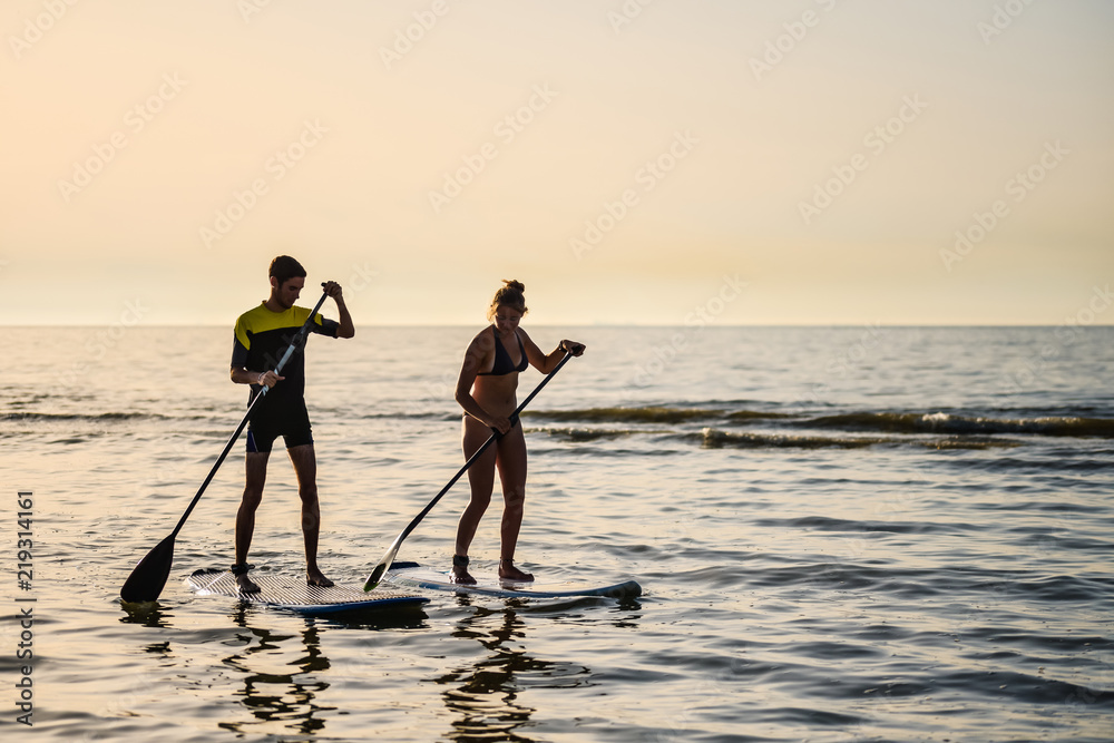 jeune couple de surfeur au coucher du soleil