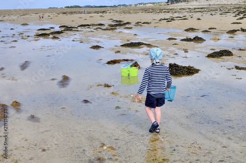 Un petit garçon qui pêche des crabes à marée basse en Bretagne photo