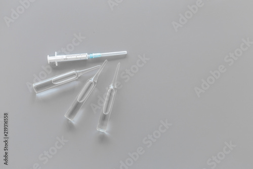 Flu vaccination concept. Syringe and ampoulie on grey background top view space for text