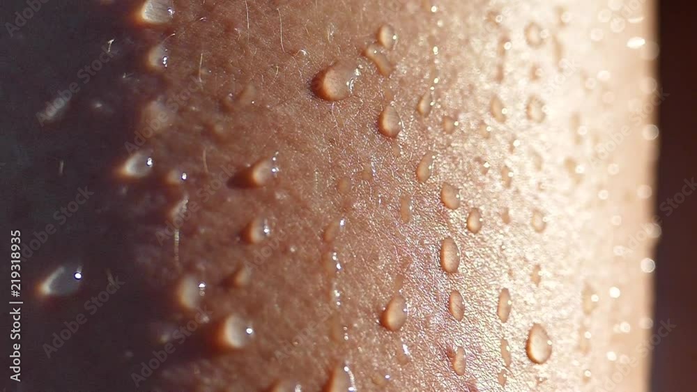 Drops of water on a wet tanned body. A hand slides over the bare shoulder of a woman.