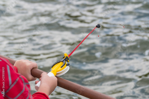 A child's hand is fishing on a small fishing rod. Ozernaya fishing. photo