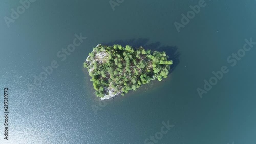 4K HD Aerial view camera moves down descending above green forest island filming directly down bellow during sunny summer day. Kangasala. Finland. Scandinavia. photo