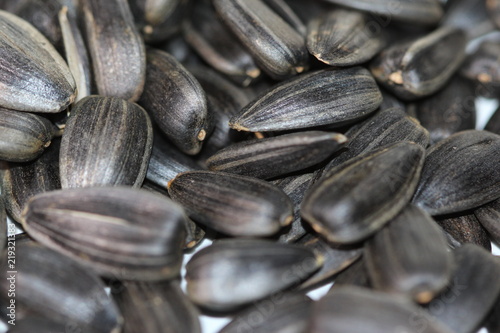 Black sunflower seeds. For texture or background. Seed sunflower. Collection of black sunflower seeds isolated on white. Pile of black sunflower seeds. Roasted seeds. Close-up of delicious sunflowers.