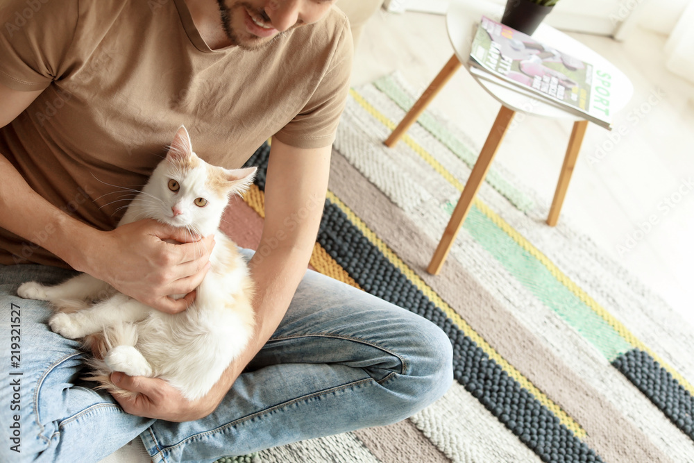 Young man with cute cat sitting on floor at home Young man with cute cat sitting on floor at home