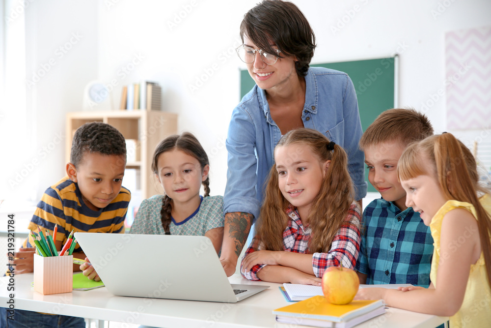 Female teacher helping children with assignment at school Female teacher helping children with assignment at school