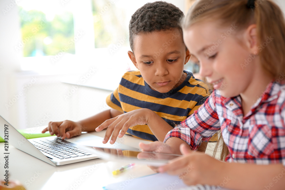 Cute little children with gadgets sitting at desk in classroom. Elementary school Cute little children with gadgets sitting at desk in classroom. Elementary school