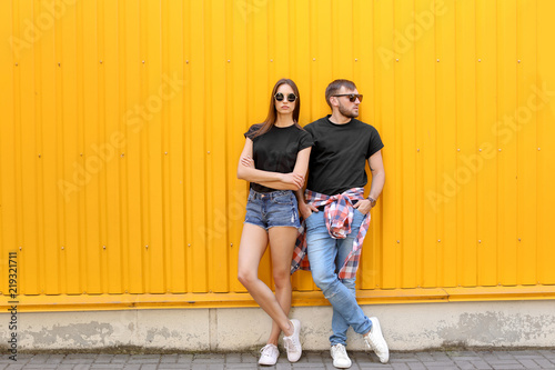 Young couple wearing black t-shirts near color wall on street