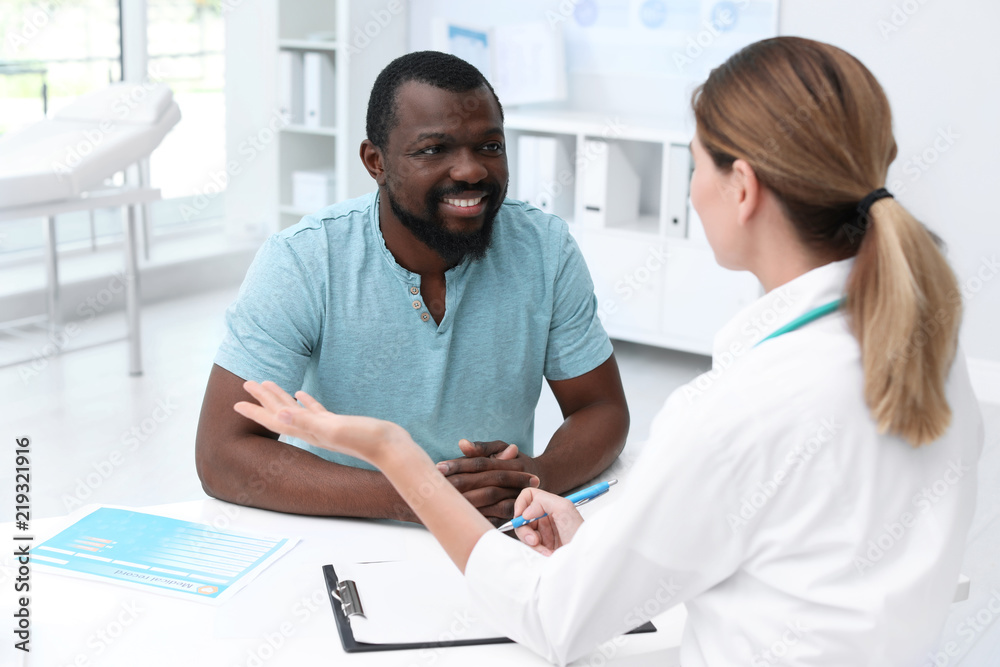 Young doctor speaking to African-American patient in hospital Young doctor speaking to African-American patient in hospital