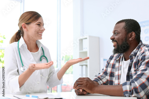 Young doctor speaking to African-American patient in hospital