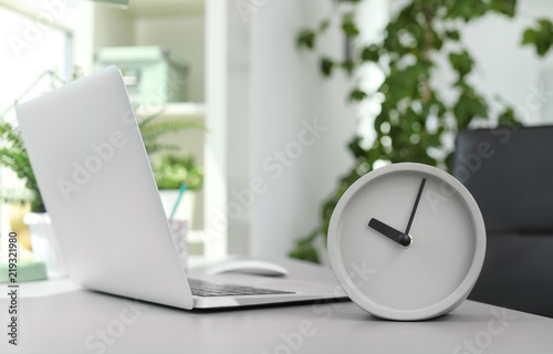 Analog alarm clock on table in office. Time to work photo