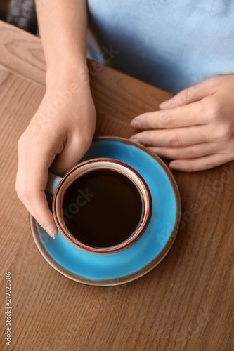Woman with cup of fresh aromatic coffee at table, top view