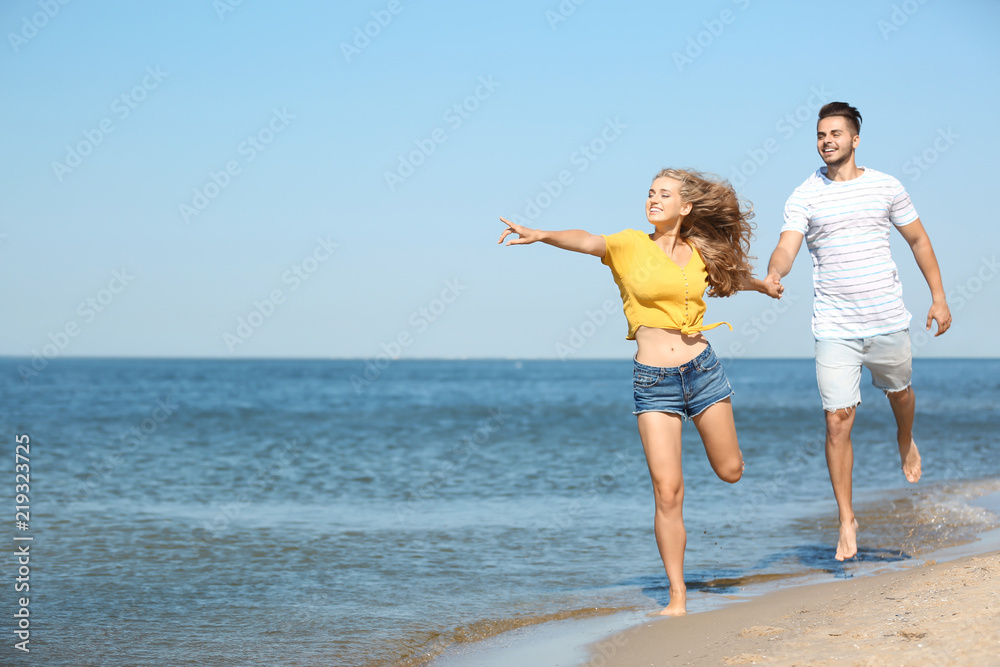 Happy young couple walking at beach on sunny day Happy young couple walking at beach on sunny day