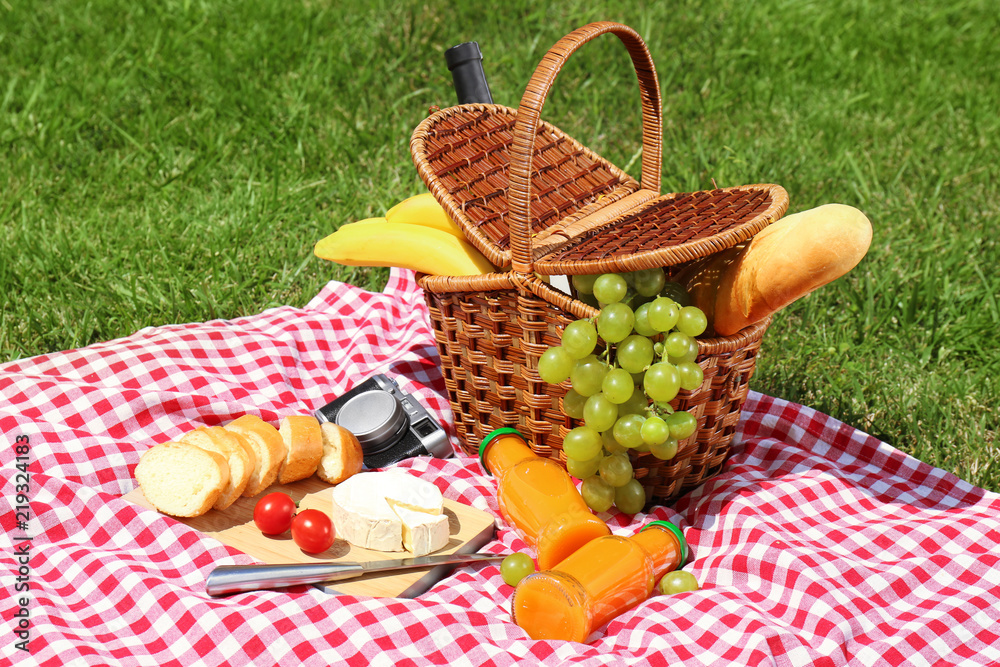 Basket with food on blanket prepared for picnic in park