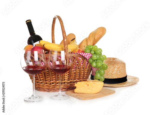 Picnic basket with food and glasses of wine on white background