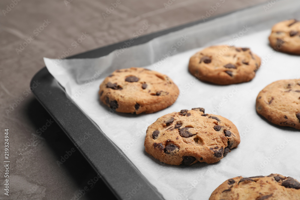 Baking sheet with chocolate chip cookies on grey background, closeup Baking sheet with chocolate chip cookies on grey background, closeup