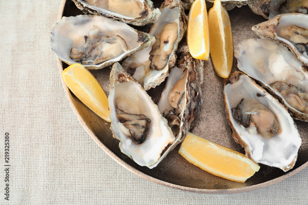 Fresh oysters with cut juicy lemon on plate, top view Fresh oysters with cut juicy lemon on plate, top view