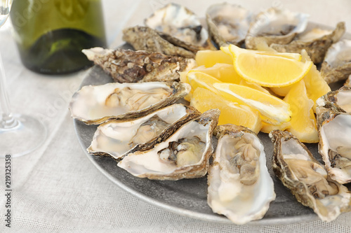 Fresh oysters with cut juicy lemon on plate, closeup